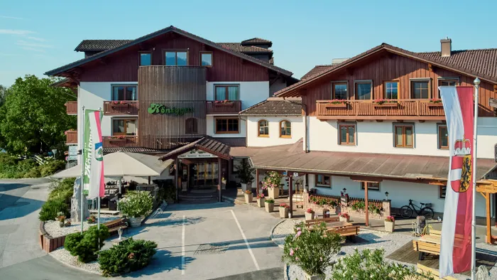 Traditionelles Alpenhotel Königgut mit Holzbalkonen und österreichischen Fahnen im Sommer